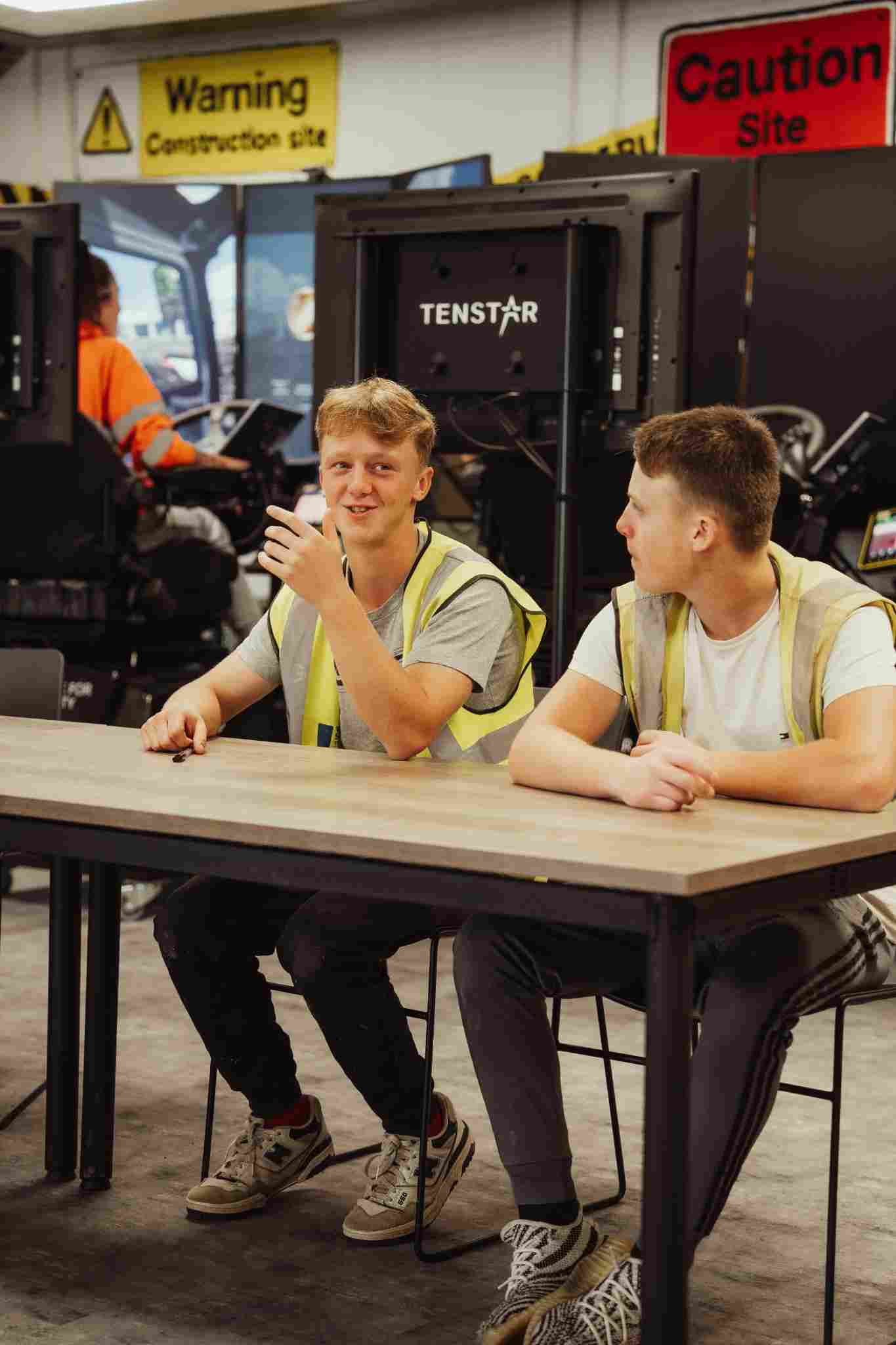 Two bricklaying apprentices sitting at a desk engaging in a lesson at the AccXel Construction School in Gloucestershire
